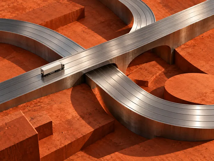 A miniature freight vehicle moving across an interconnected sculptural network of chrome roads and terracotta terrain